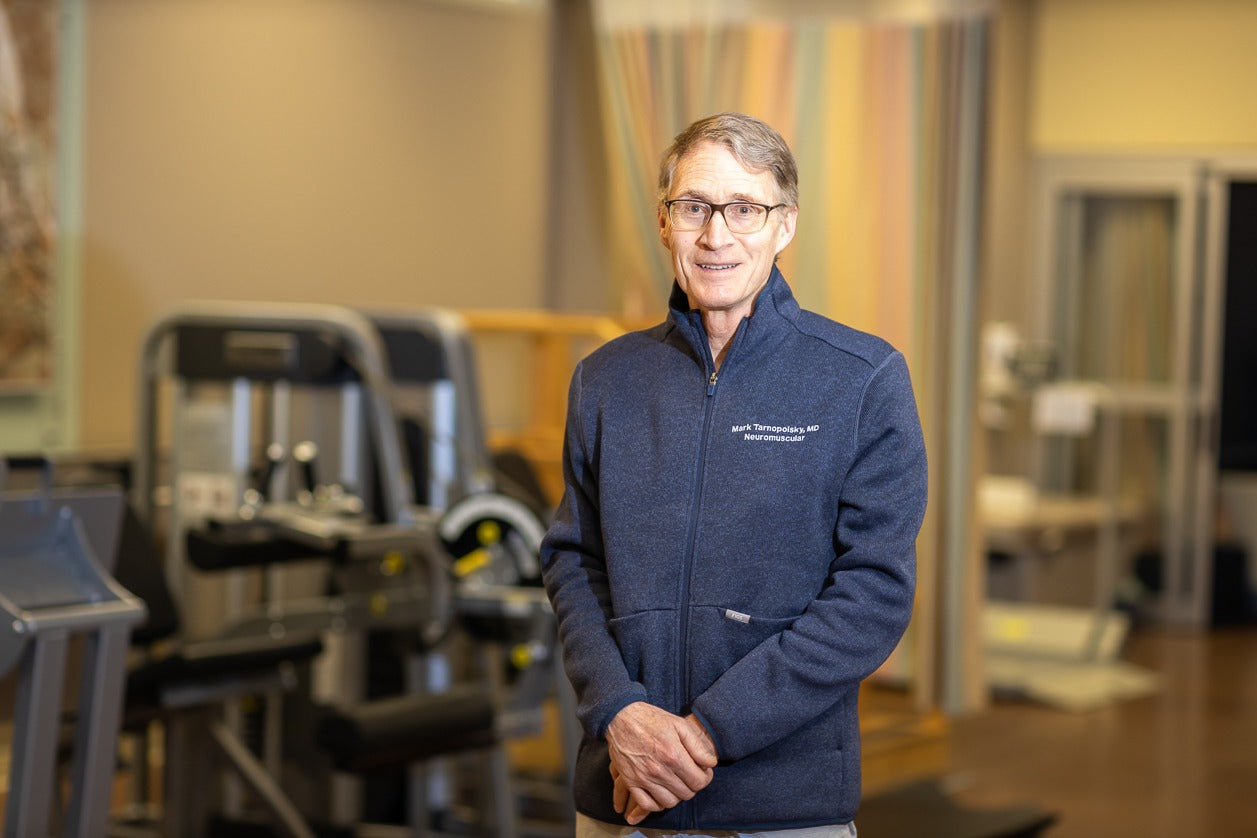 Man wearing a navy blue jacket with a logo in a gym setting
